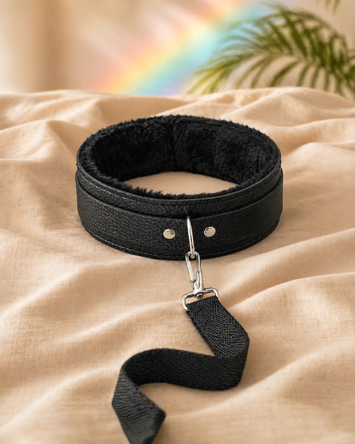 Black bondage collar and leash resting on soft bedding, comfortable restraint collar with adjustable fit and secure clip