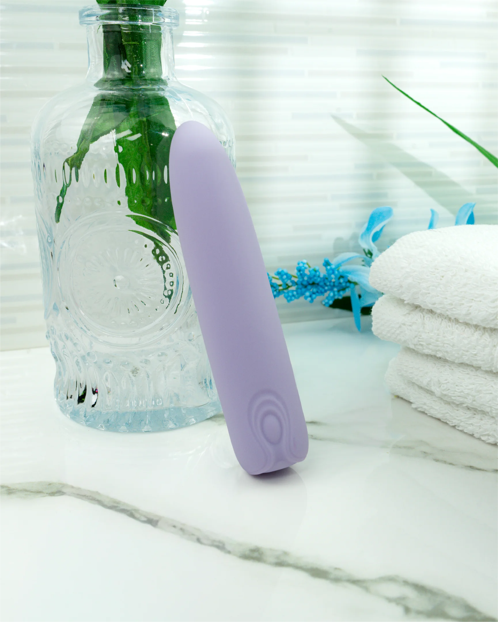 Pastel purple Hyacinth mini bullet vibrator on marble surface with towels and glass bottle, waterproof silicone vibrator