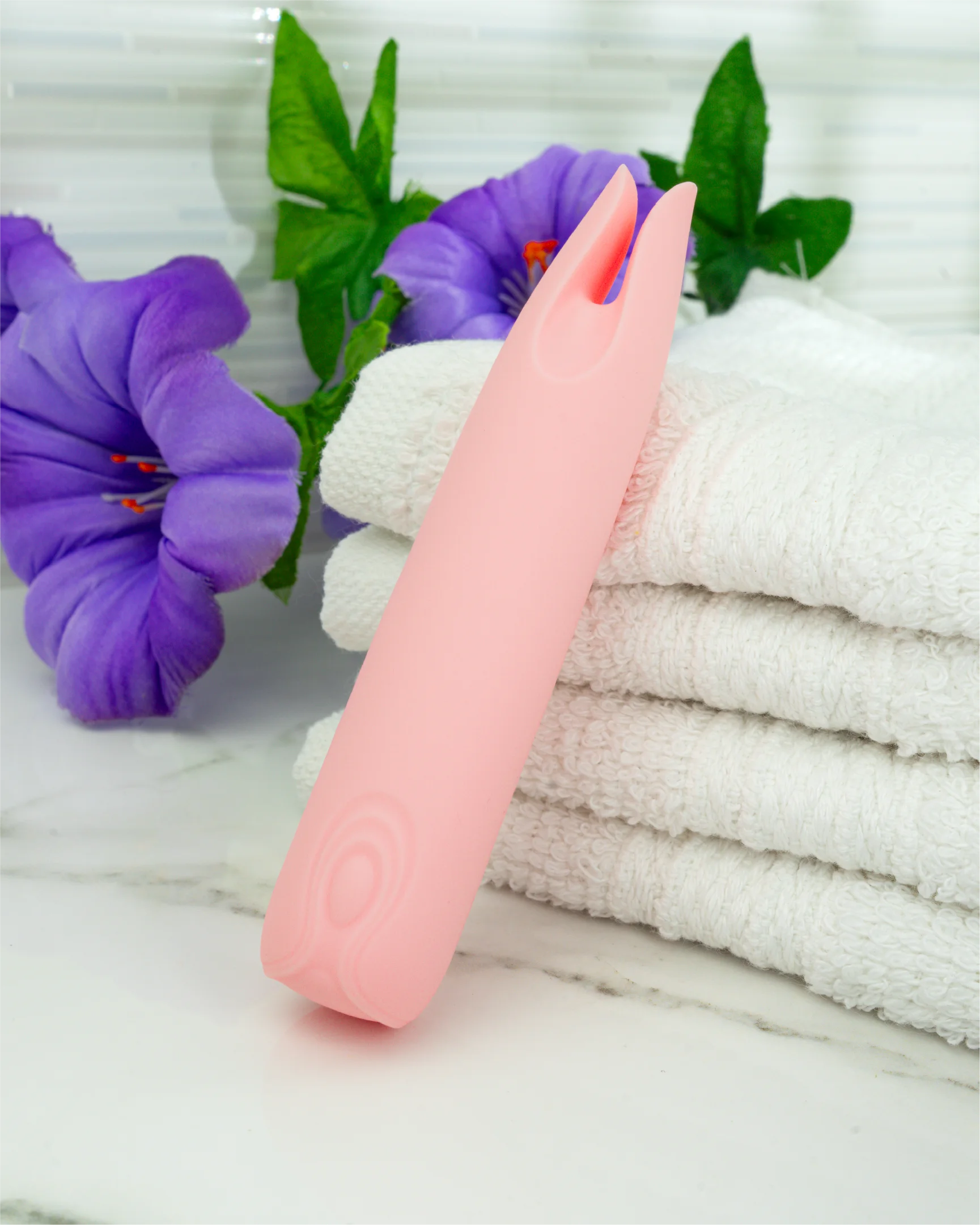 Blush & Bloom Petunia dual-tip clitoral vibrator in pastel pink on folded towels, soft silicone waterproof mini vibrator