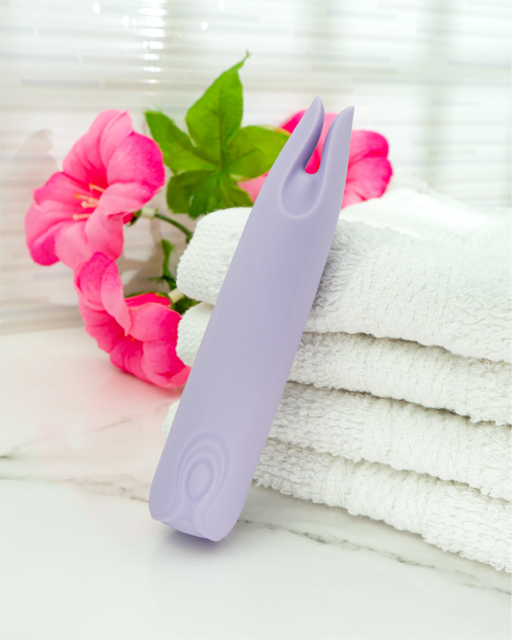 Blush & Bloom Petunia dual-tip clitoral vibrator in pastel purple standing on folded towels, compact waterproof silicone mini vibrator