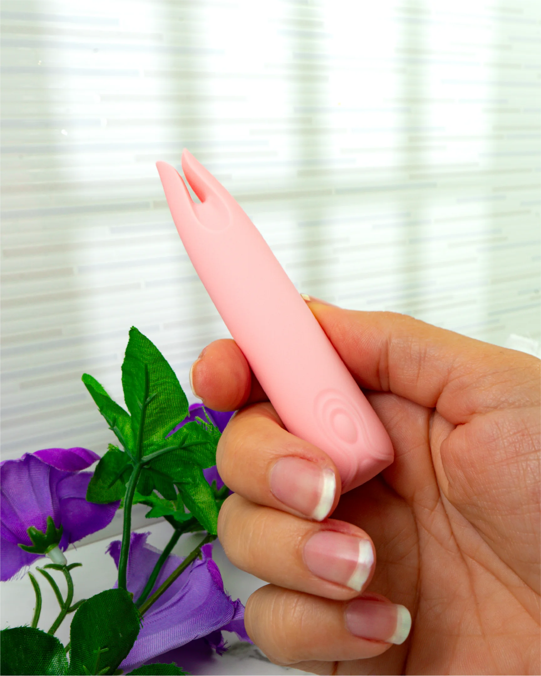 Close-up of hand holding pastel pink Blush & Bloom Petunia dual-tip vibrator showing compact beginner-friendly design
