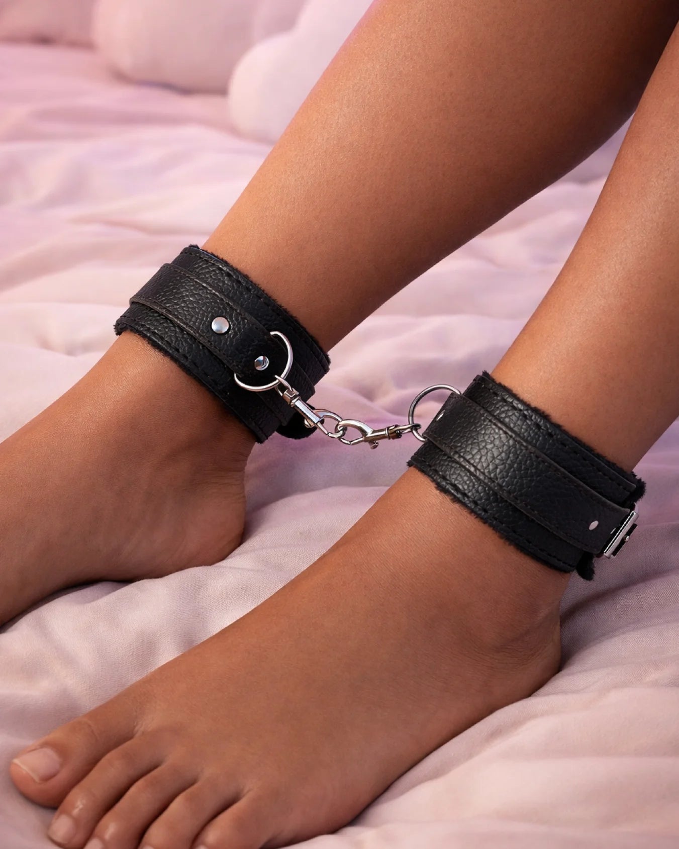 Black fur-lined ankle cuffs worn on ankles with adjustable straps for controlled and comfortable bondage play