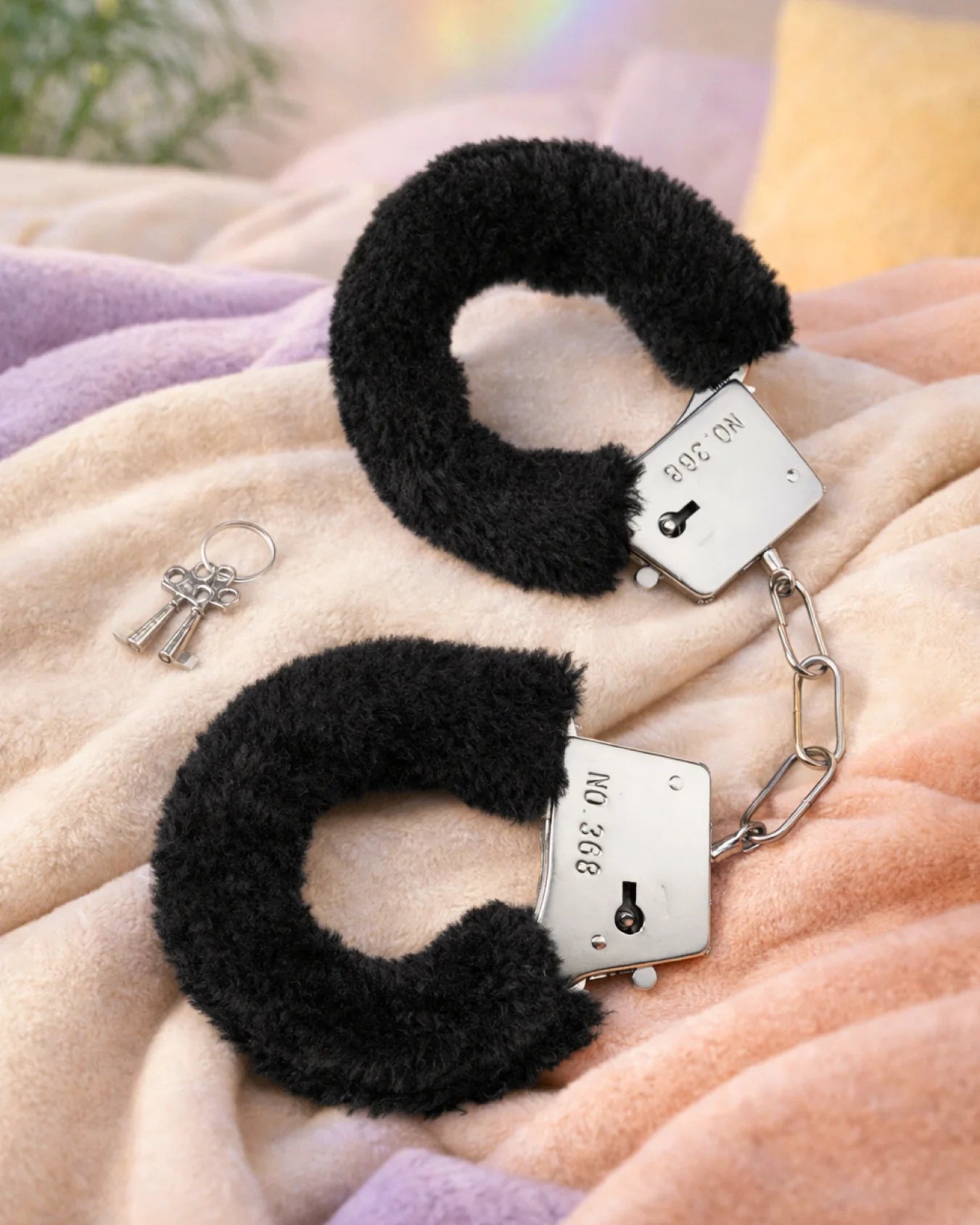 Black BDSM furry handcuffs with plush lining and metal cuffs on bed for classic bondage restraint and secure adjustable fit
