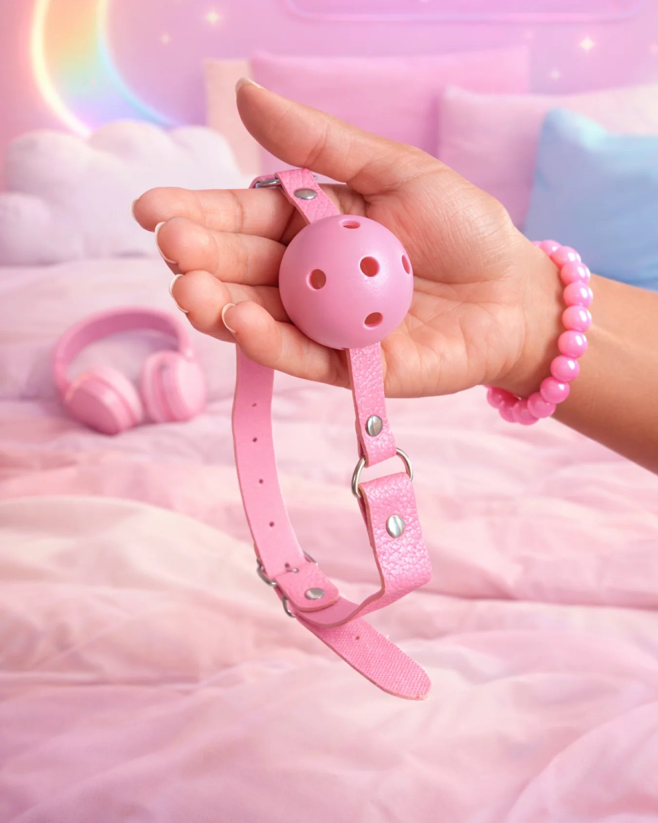 Pink breathable ball gag by Empower Play™ held in hand showing size, airflow holes, and adjustable strap for comfortable mouth restraint