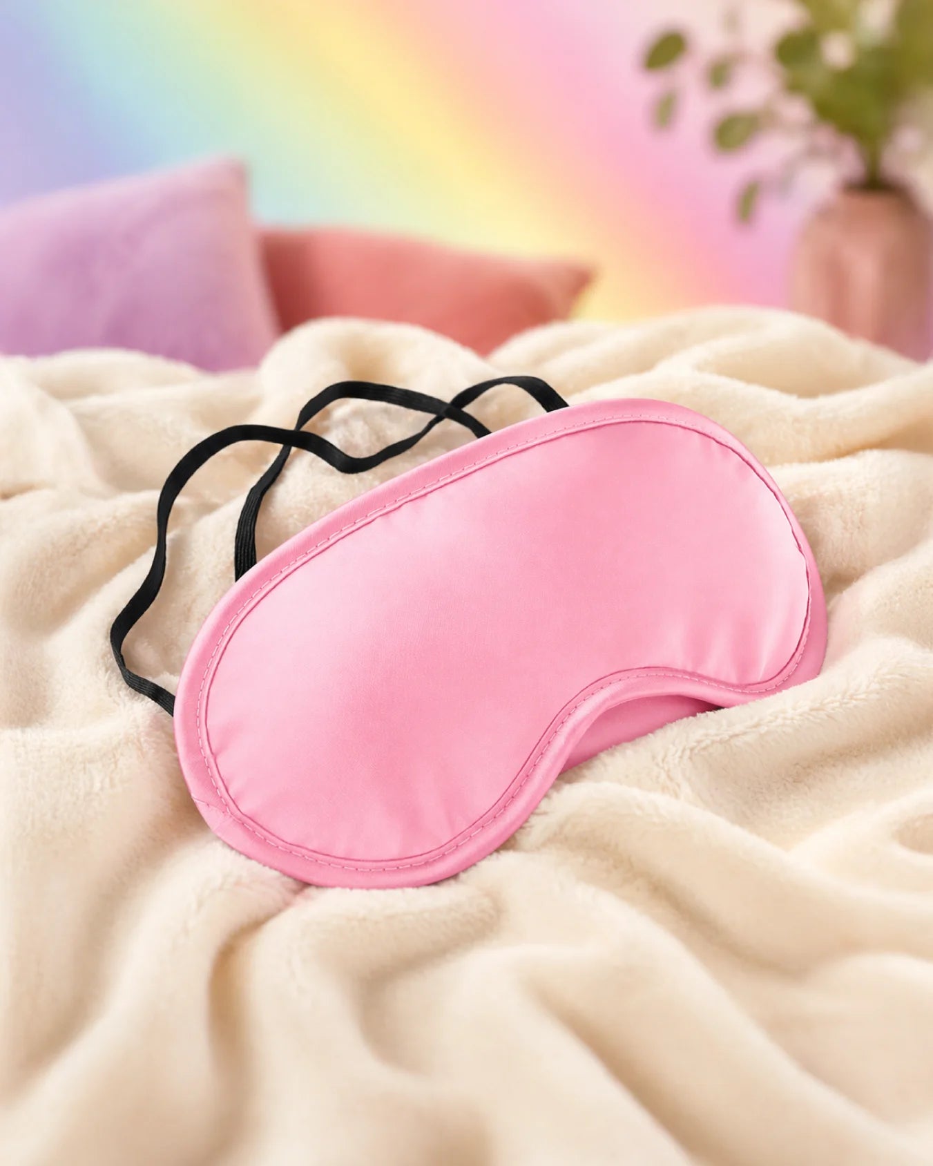 Pink satin blindfold resting on bed designed for soft sensory deprivation and smooth fabric comfort