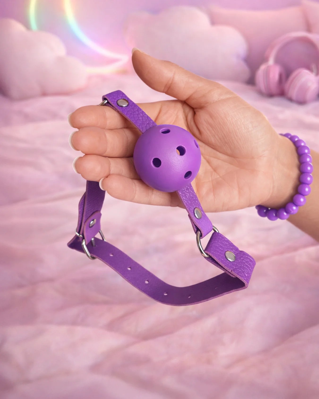 Purple breathable ball gag in hand displaying size, airflow design, and adjustable strap for comfortable BDSM mouth restraint