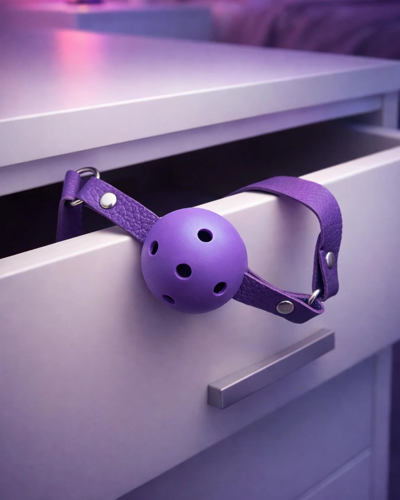Purple breathable ball gag with airflow holes shown in bedroom setting, soft yet structured mouth gag design