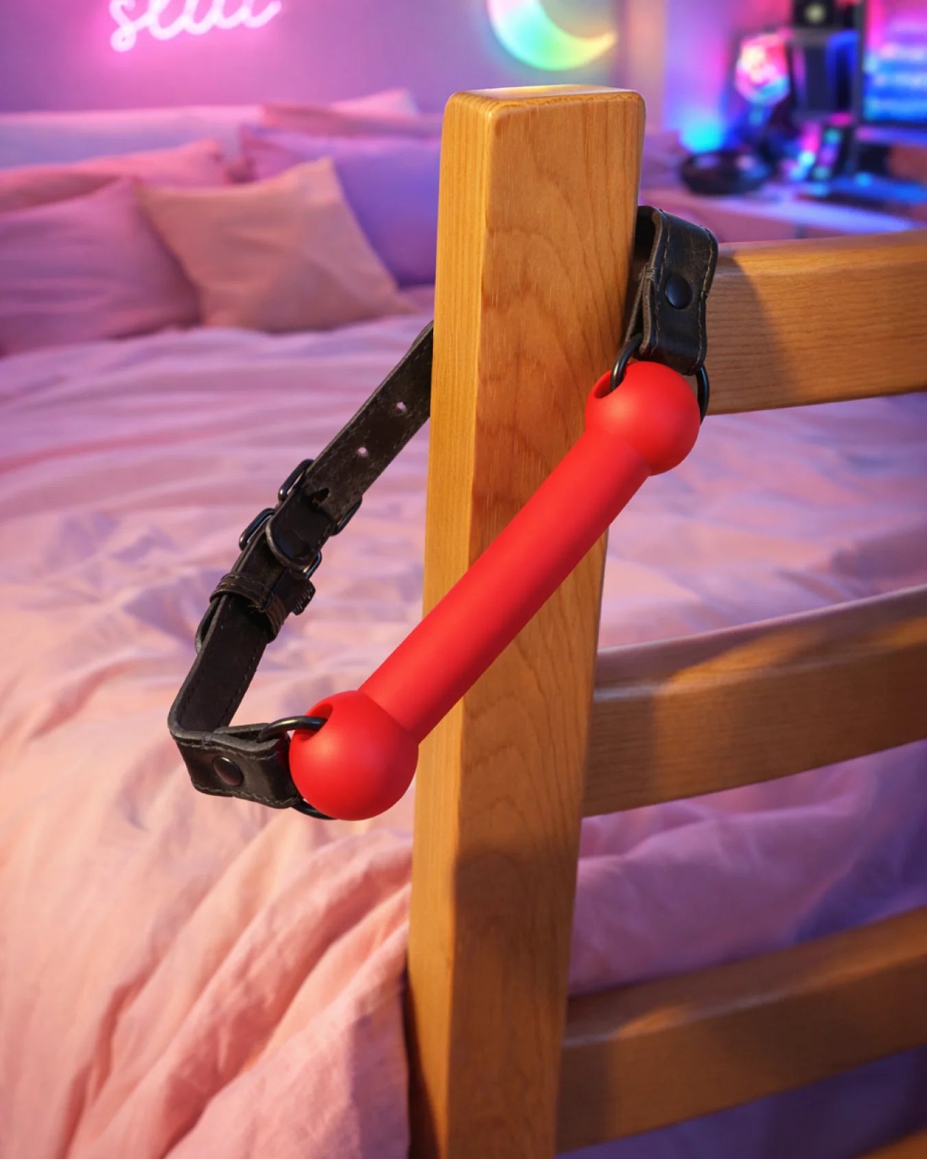 Red silicone bit gag placed on bedpost with adjustable strap, expressive yet comfortable restraint option
