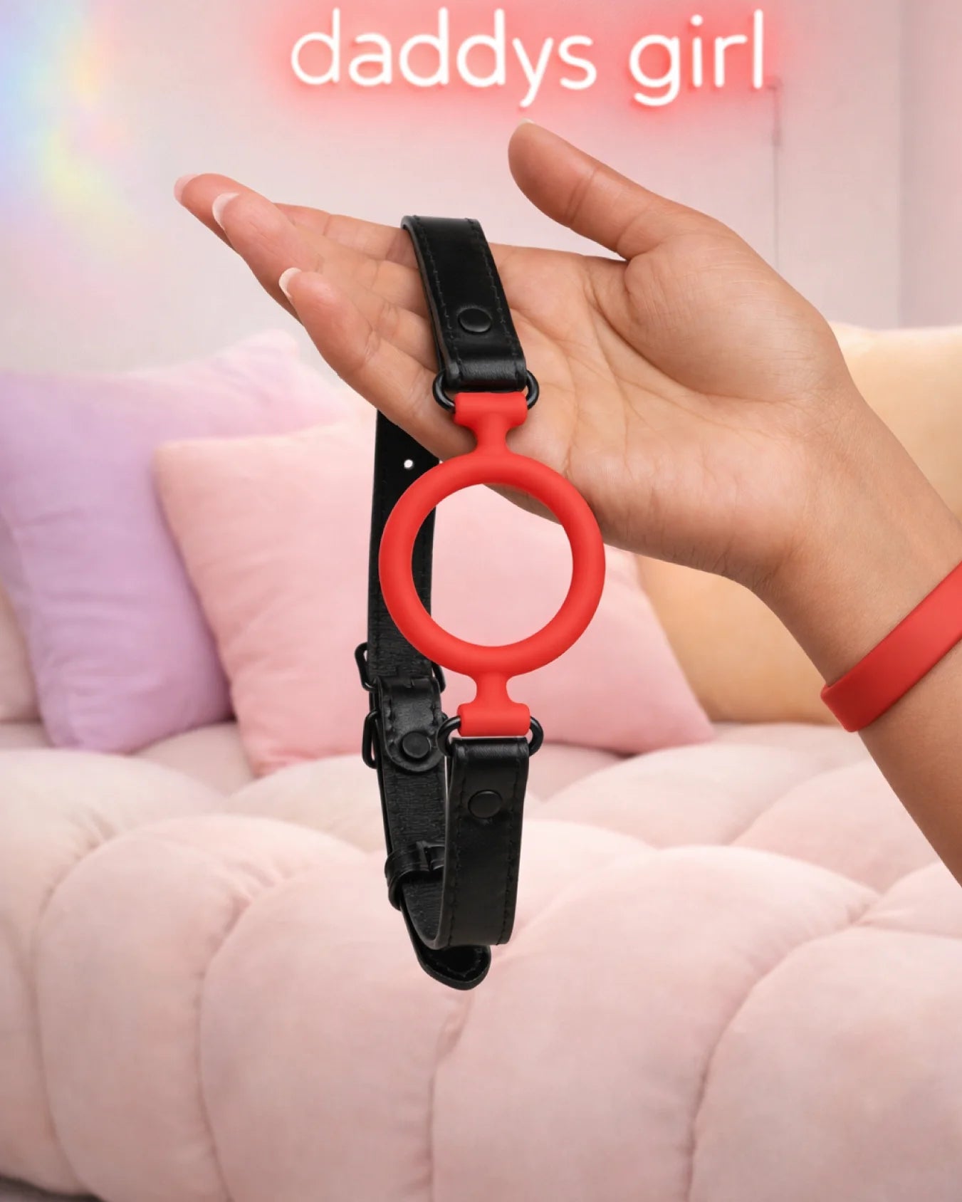 Red silicone O-ring gag in hand showing size, breathable open-mouth design, and adjustable strap fit