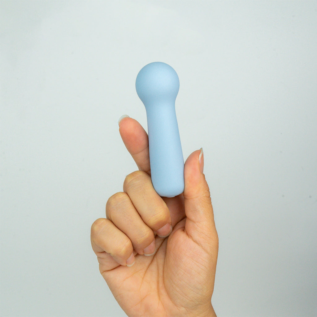 Joy Penny blue mini wand clitoral massager shown in hand to demonstrate small size and easy handling