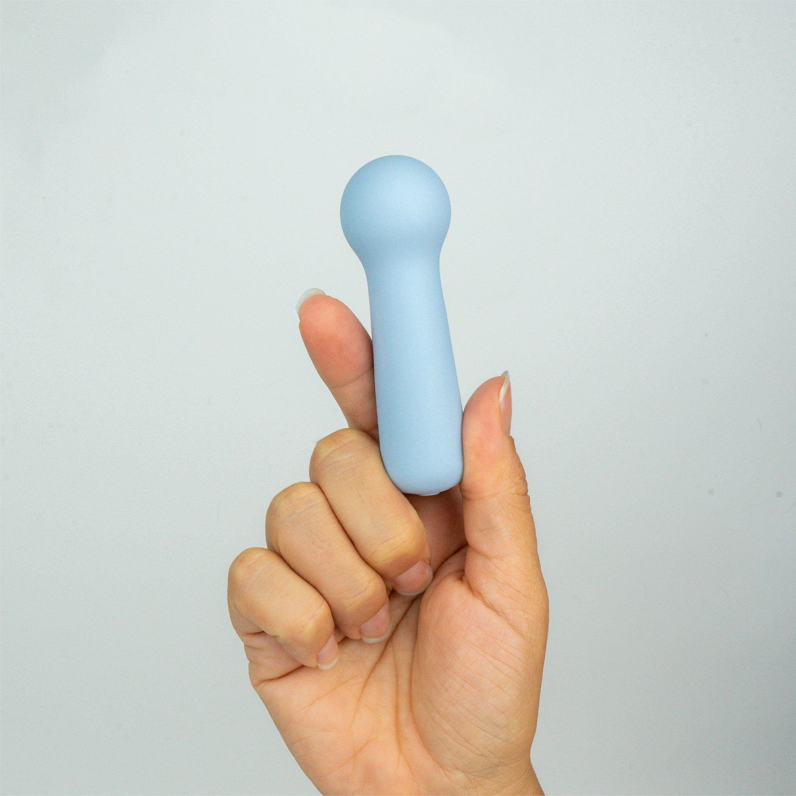 Joy Penny blue mini wand clitoral massager shown in hand to demonstrate small size and easy handling