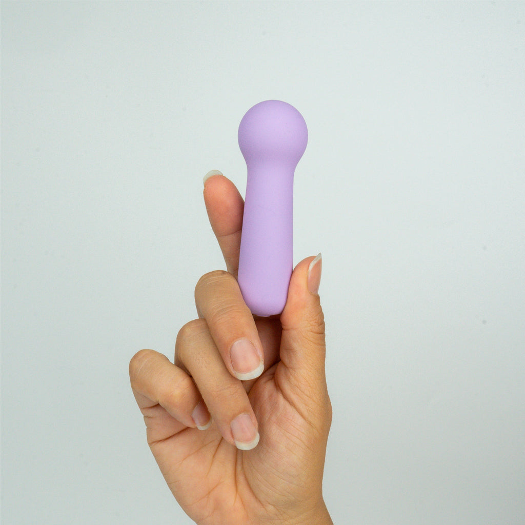 Joy Penny mini wand clitoral massager in pastel purple in hand showing compact size and comfortable grip