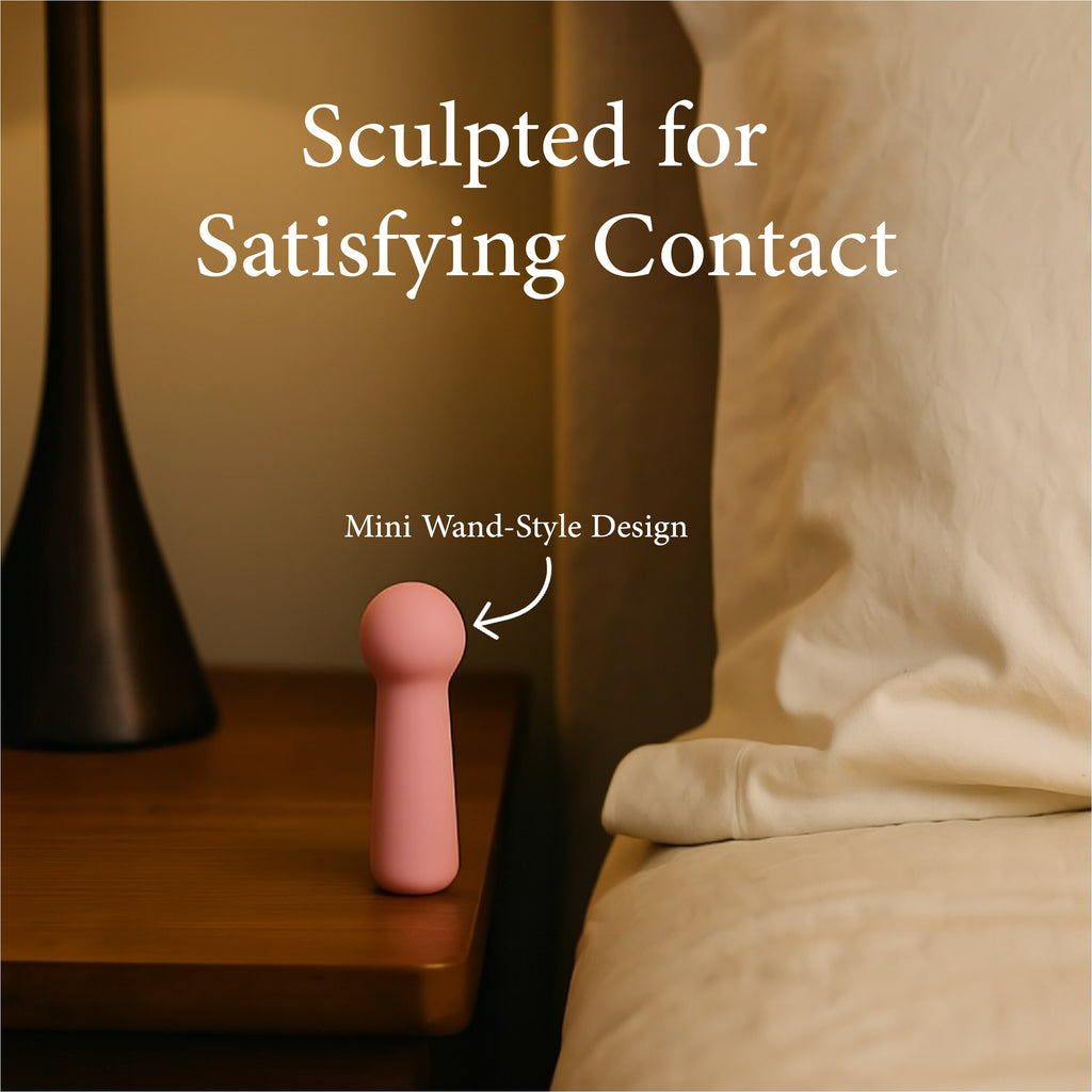 Joy Penny mini wand vibrator in pastel pink placed on bedside table highlighting compact wand style design