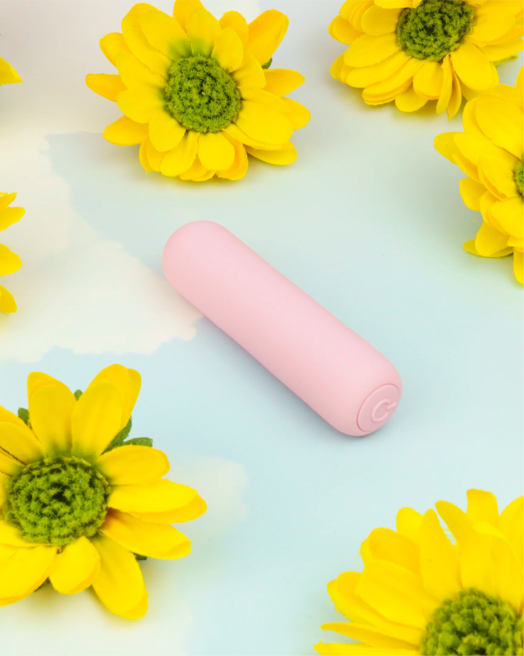 Pastel pink Joy Pippa rechargeable bullet vibrator in clean flat lay with flowers, sleek compact shape designed for targeted stimulation and everyday use