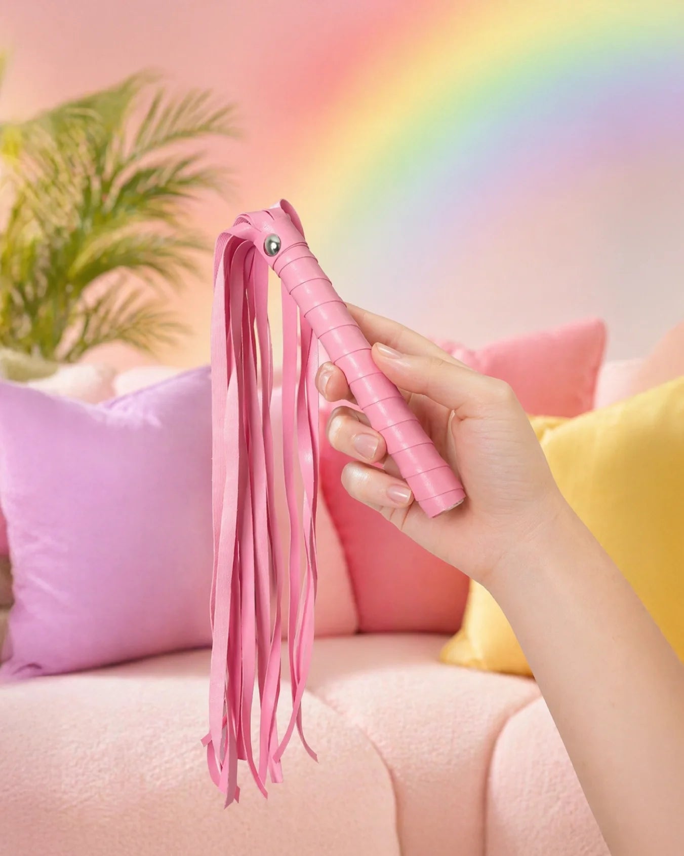 Hand holding pink faux leather BDSM flogger showing grip and flexible tails for beginner spanking play