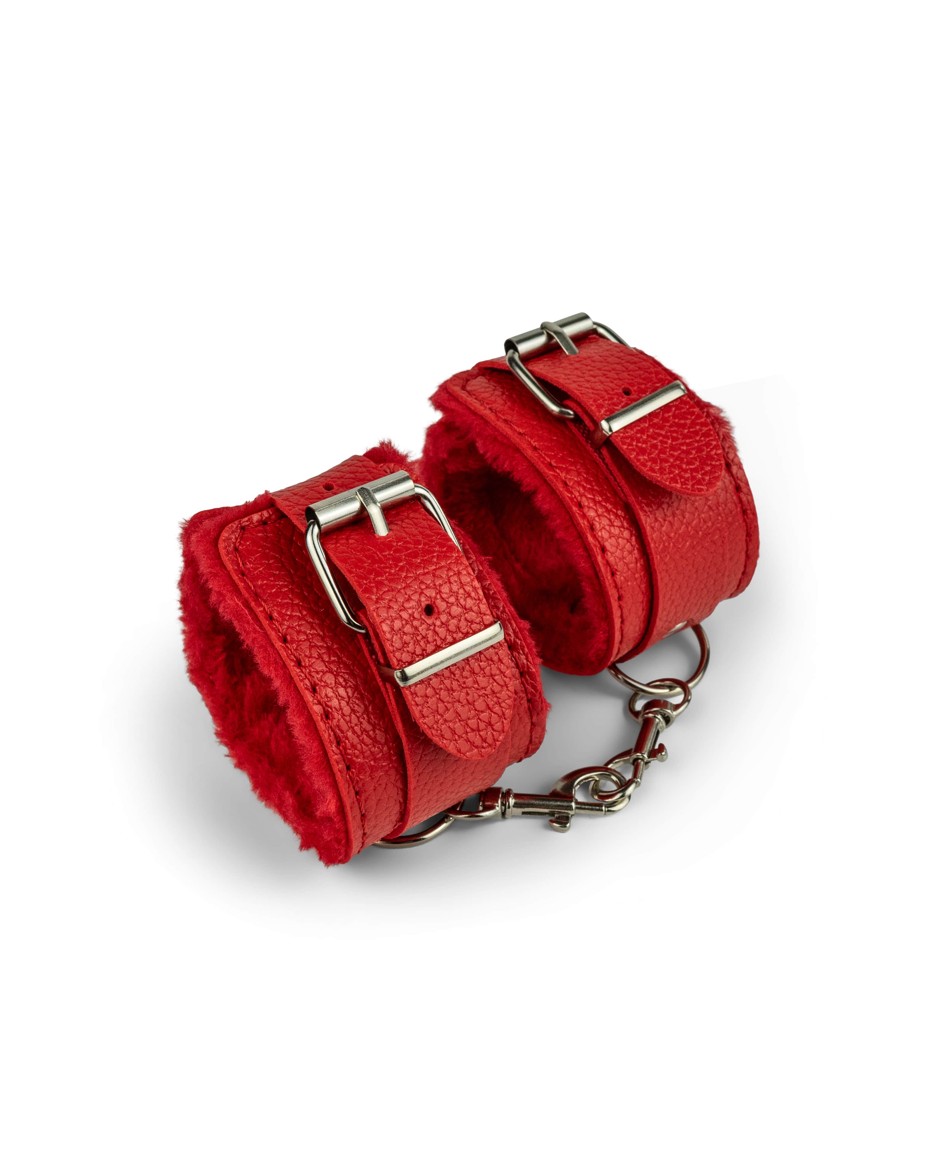 Scarlet red fur-lined wrist restraints with padded cuffs and metal chain, designed for beginner bondage and playful restraint